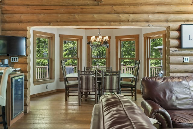 living area with beverage cooler, wood finished floors, baseboards, rustic walls, and an inviting chandelier