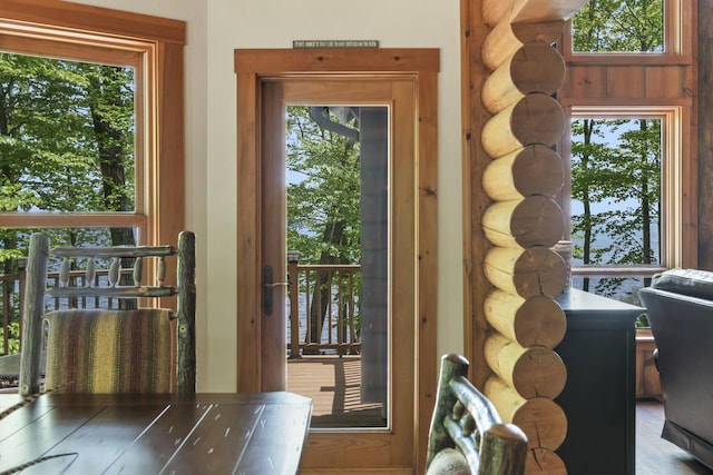 doorway to outside with a wealth of natural light and log walls