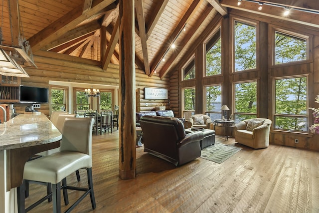 living area featuring high vaulted ceiling, beamed ceiling, wood-type flooring, and a notable chandelier