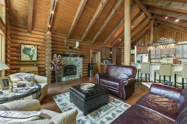 living room featuring hardwood / wood-style flooring, high vaulted ceiling, beamed ceiling, and a stone fireplace