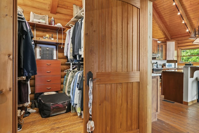 spacious closet with lofted ceiling with beams and hardwood / wood-style flooring