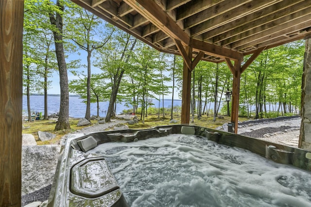 exterior space with a water view and a hot tub