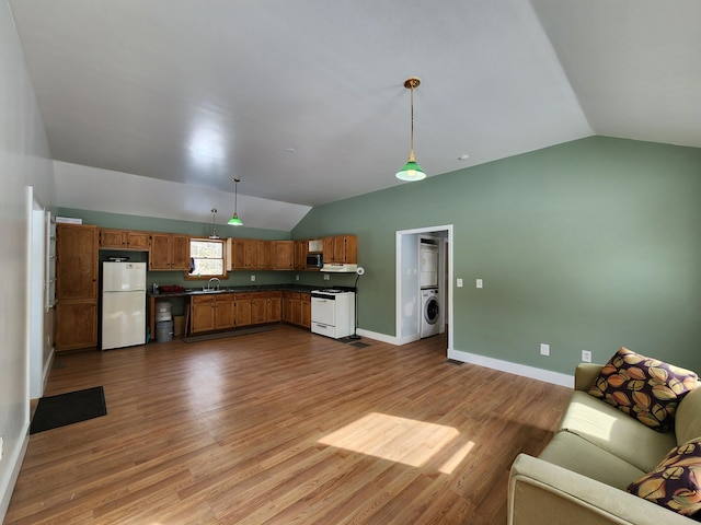 kitchen with lofted ceiling, a sink, freestanding refrigerator, washer / clothes dryer, and dark countertops