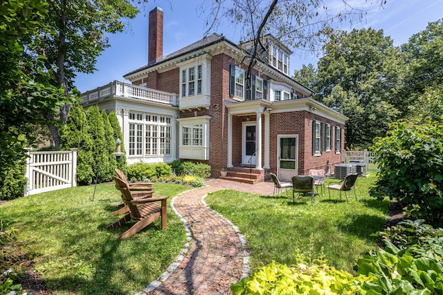 rear view of house featuring a lawn, a chimney, a gate, fence, and brick siding