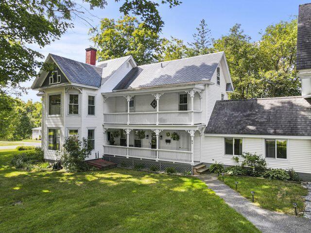 rear view of house featuring a yard, a chimney, and a balcony