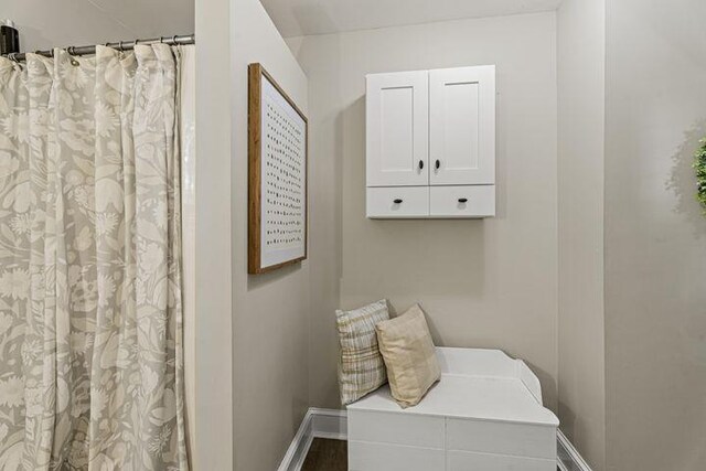 interior space with a shower with curtain and baseboards