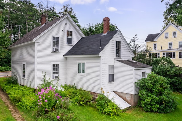 rear view of house with a chimney and cooling unit