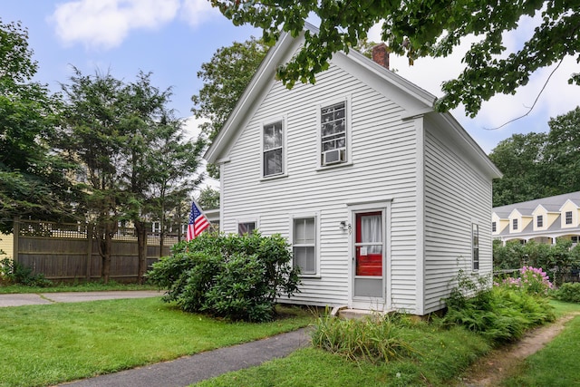 view of front of home with a chimney, fence, and a front yard