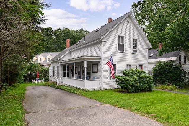 view of front of property featuring a front lawn, a chimney, and a porch