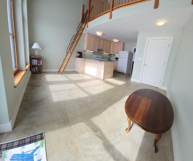 living area with a high ceiling, concrete flooring, and baseboards