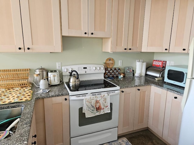 kitchen with white appliances, dark stone counters, and a sink