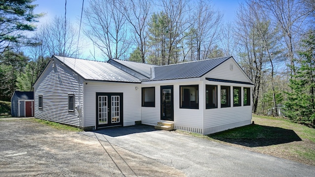 ranch-style house featuring metal roof, french doors, an outbuilding, a sunroom, and a shed