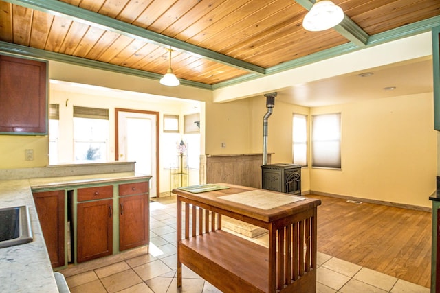 kitchen with a wood stove, light tile patterned floors, wood ceiling, and light countertops