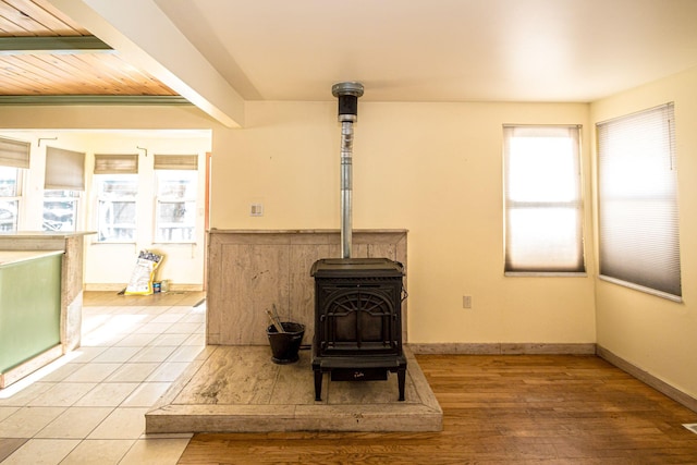 interior details with wood finished floors, a wood stove, and baseboards