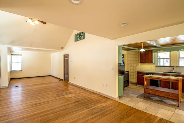 kitchen with light wood-type flooring, ceiling fan, baseboards, and a sink