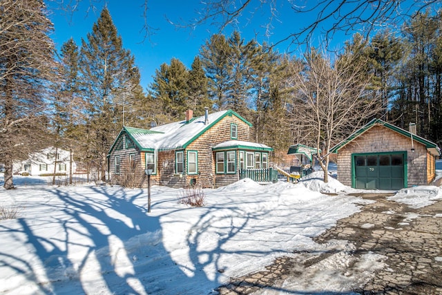 view of front of home featuring a garage, driveway, a chimney, and an outdoor structure