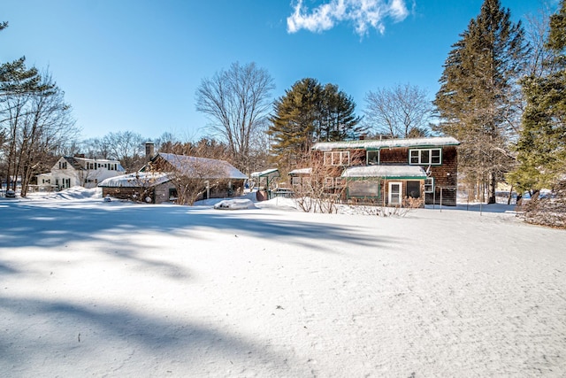 snow covered back of property with gravel driveway