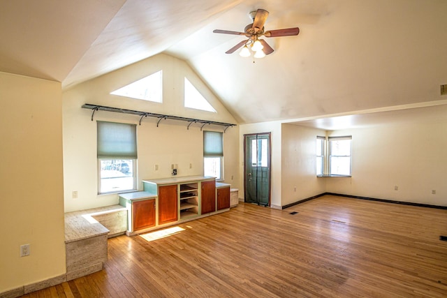 unfurnished living room featuring baseboards, ceiling fan, high vaulted ceiling, and light wood-style floors