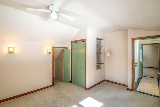 unfurnished bedroom with lofted ceiling, a closet, light carpet, and baseboards