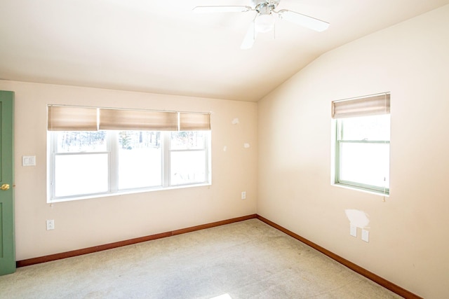 carpeted spare room with lofted ceiling, plenty of natural light, a ceiling fan, and baseboards