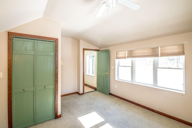 unfurnished bedroom featuring lofted ceiling, ceiling fan, baseboards, and light colored carpet