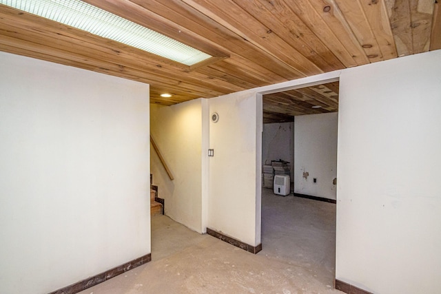 finished below grade area featuring wood ceiling, stairs, and baseboards