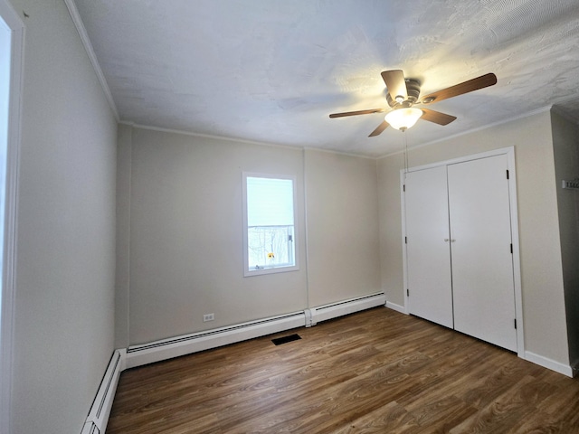 unfurnished bedroom featuring dark wood-type flooring, a baseboard radiator, a ceiling fan, and crown molding