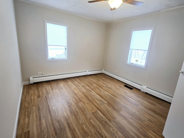 spare room featuring a ceiling fan, crown molding, baseboard heating, and wood finished floors