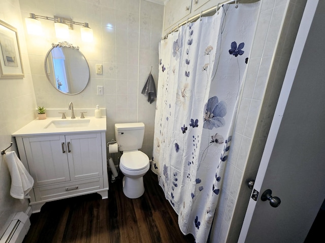 bathroom with toilet, a baseboard heating unit, wood finished floors, vanity, and tile walls