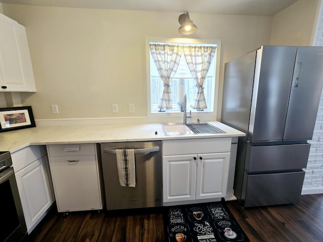 kitchen with stainless steel appliances, a sink, white cabinets, light countertops, and dark wood-style floors