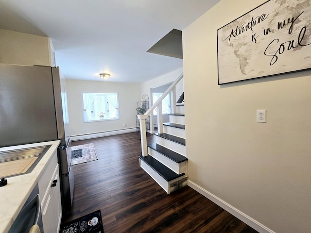 staircase featuring a baseboard radiator, baseboards, and wood finished floors