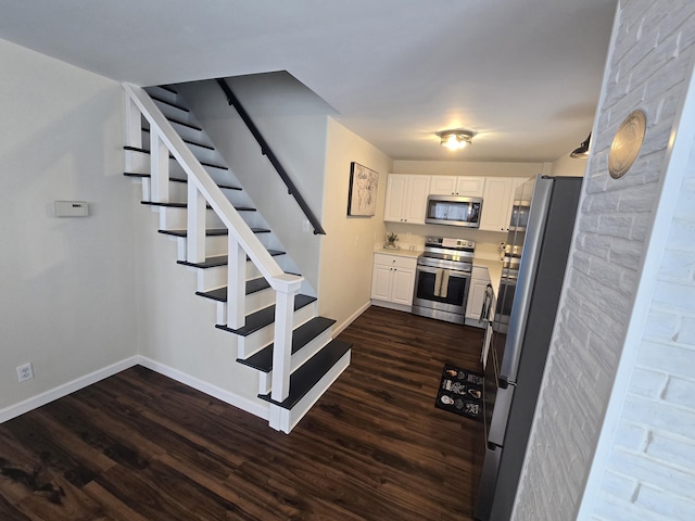 interior space with baseboards, appliances with stainless steel finishes, dark wood-type flooring, light countertops, and white cabinetry