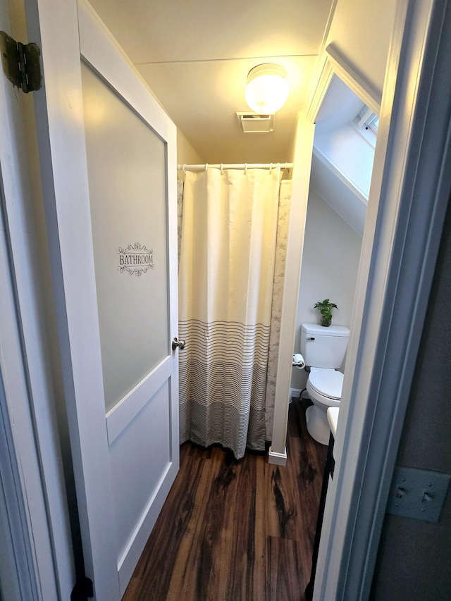 bathroom featuring visible vents, toilet, a shower with curtain, wood finished floors, and vaulted ceiling