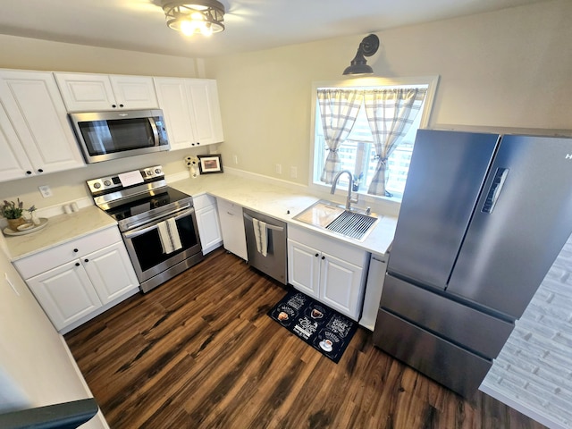 kitchen with dark wood finished floors, white cabinetry, stainless steel appliances, and a sink