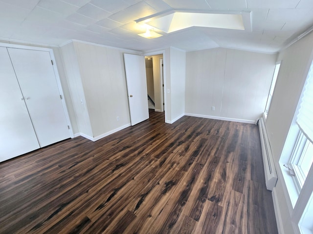 interior space featuring vaulted ceiling, baseboard heating, dark wood finished floors, and baseboards