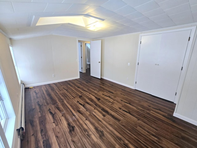 interior space with dark wood-type flooring, a baseboard heating unit, and baseboards