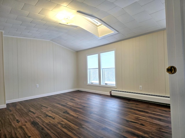 unfurnished room featuring vaulted ceiling with skylight, dark wood-style floors, a baseboard radiator, and ornamental molding