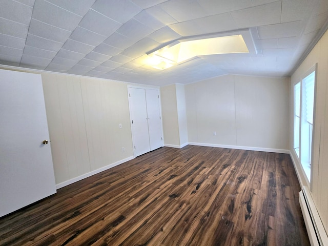 spare room with a baseboard heating unit, dark wood-style floors, and baseboards