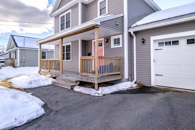 exterior space featuring a porch, an attached garage, and aphalt driveway