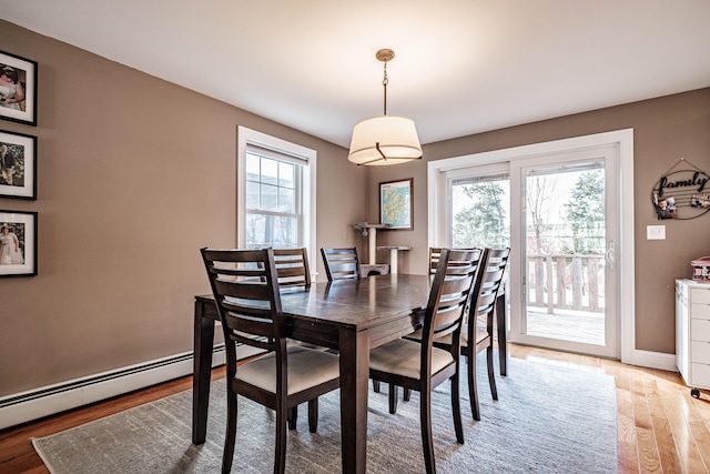 dining room featuring baseboard heating, baseboards, and light wood finished floors