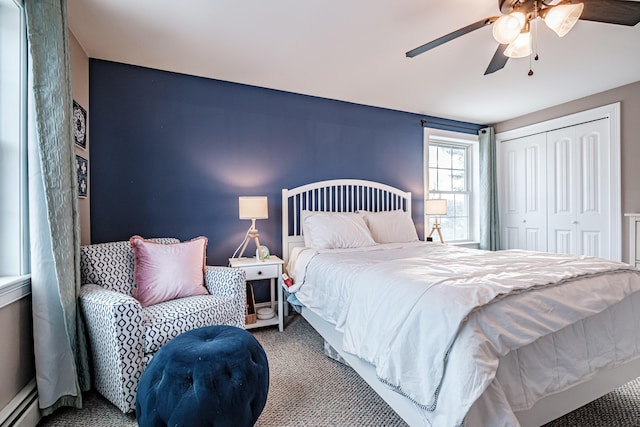 carpeted bedroom with a ceiling fan, baseboard heating, and a closet