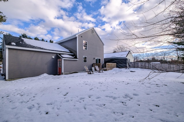 snow covered back of property featuring a garage