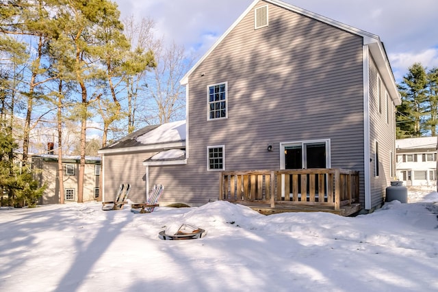 snow covered house with a fire pit and a wooden deck