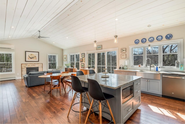 kitchen with gray cabinets, a sink, appliances with stainless steel finishes, lofted ceiling, and baseboard heating