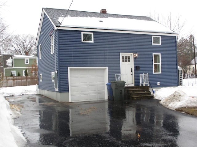 view of front of property with aphalt driveway, a chimney, a shingled roof, and fence