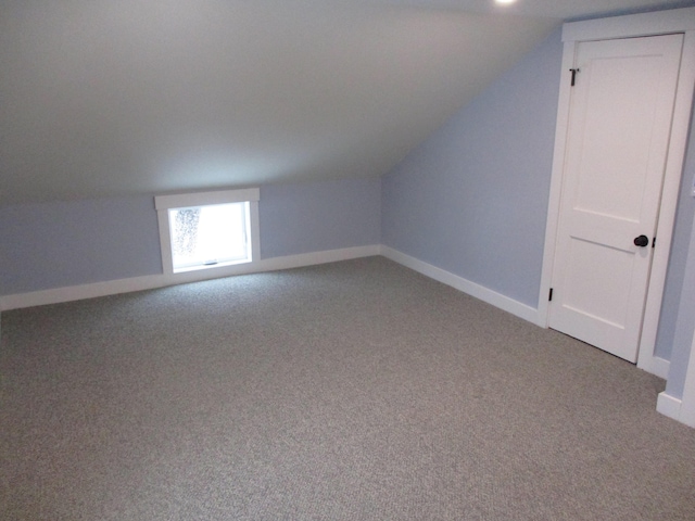 additional living space featuring light carpet, baseboards, and vaulted ceiling