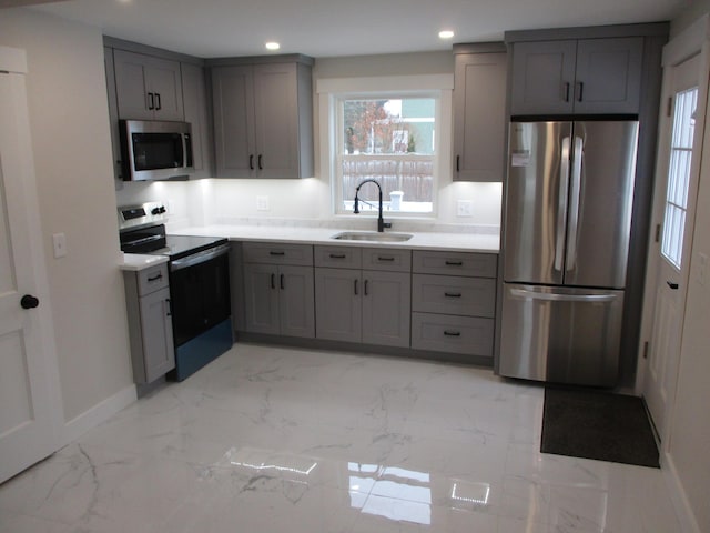 kitchen with marble finish floor, stainless steel appliances, a sink, and gray cabinetry