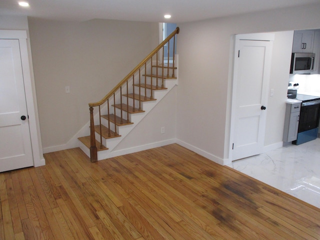 stairway featuring hardwood / wood-style floors, recessed lighting, and baseboards