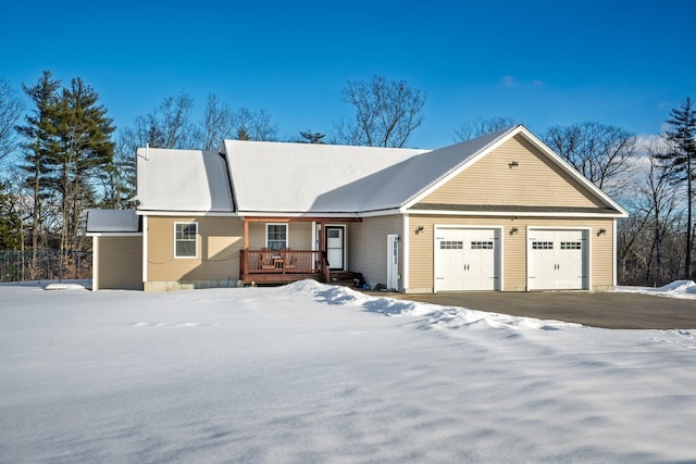 single story home with driveway, a deck, and an attached garage