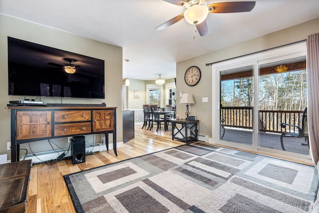 living area with baseboards, a baseboard heating unit, ceiling fan, and wood finished floors